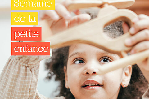 Petite fille qui joue avec un hélicoptère en bois