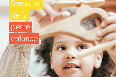 Petite fille qui joue avec un hélicoptère en bois