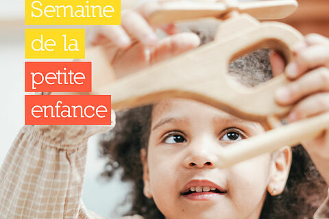 Petite fille qui joue avec un hélicoptère en bois