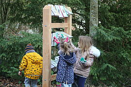 Enfants de dos qui regardent une table patrimoniale dans le jardin du Clos Poincaré